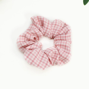 Close-up of pink and white gingham fabric scrunchie with soft ruffled texture