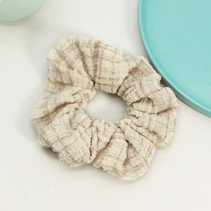 Detail of cream plaid tweed scrunchie with subtle golden metallic threads and soft texture