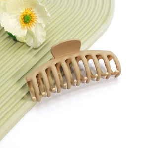 Vue détaillée d'une grande pince à cheveux beige mat sur un plateau décoratif ondulé