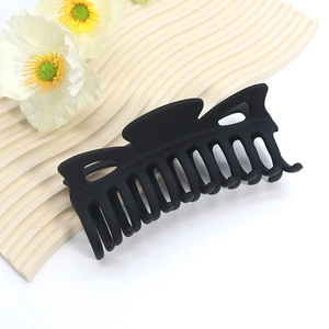 Macro detail of large matte black claw clip with multi-tooth design on a wavy tray