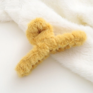 Vista dettagliata della molletta per capelli in peluche giallo con texture in finta pelliccia
