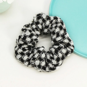 Detailed macro shot of vintage black and white plaid tweed scrunchie with gold threads