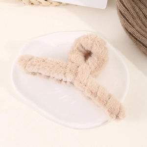 Vue macro d'une grande pince à cheveux en fausse fourrure beige sur une assiette blanche