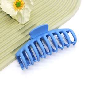 Détail d'une grande pince à cheveux bleue mate sur un fond texturé élégant
