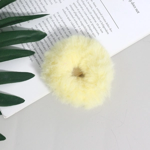 Dettaglio di un elastico per capelli in peluche giallo chiaro su sfondo decorativo
