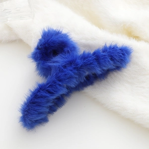 Dettaglio della morbida molletta per capelli in peluche blu Klein su pelliccia bianca