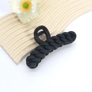 Close-up of large matte black shark hair claw clip with curb chain design on a wave board