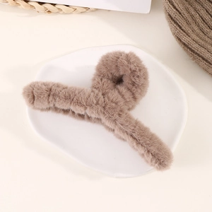 Détail macro d'une grande pince à cheveux en fausse fourrure café sur assiette blanche