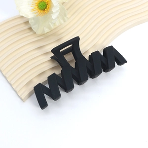 Detail of a large matte black shark hair clip with a wave-shaped geometric design