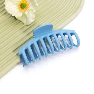 Gros plan d'une grande pince à cheveux bleu clair mate sur une surface texturée avec fleurs