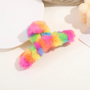 Close-up of a plush rainbow hair claw clip made of soft long faux fur on a white pedestal