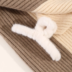 Vue macro d'une pince à cheveux en fausse fourrure blanche sur un fond en tricot chaud