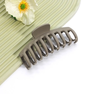 Détail de la grande pince à cheveux marron mat sur surface verte avec décor floral