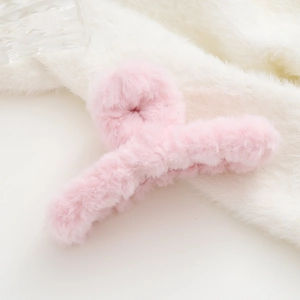 Vista dettagliata della pinza per capelli in peluche rosa chiaro su sfondo soffice