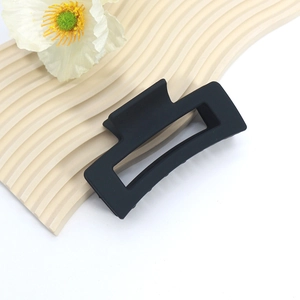 Macro detail of large matte black hollow shark hair claw clip on wavy display board