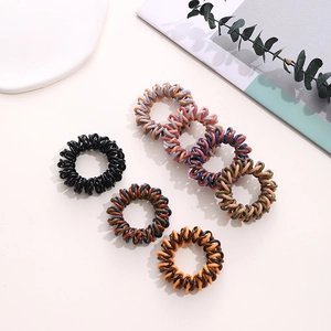 Detail of six colorful spiral hair ties on a minimalist background with aesthetic props