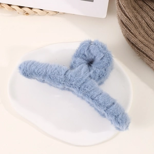 Gros plan d'une pince à cheveux en fausse fourrure bleue sur une assiette en céramique