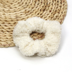 White fluffy lamb wool scrunchie on straw mat for cozy autumn winter hair styling