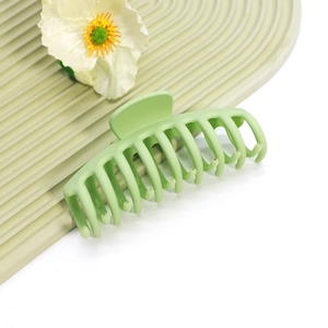Détail d'une grande pince à cheveux vert clair mat sur fond décoratif ondulé
