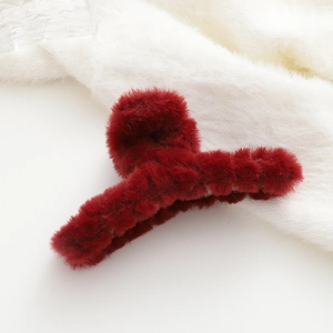Dettaglio della grande molletta per capelli in peluche rosso scuro con morbida ecopelliccia