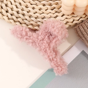 Close-up of pink lamb wool hair claw clip with plush texture on a cozy aesthetic background