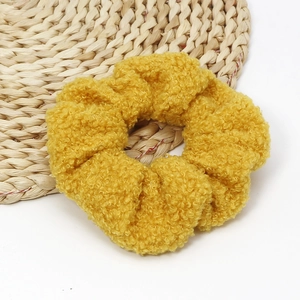 Detail of yellow fuzzy scrunchie with lamb wool texture on a woven straw mat backdrop