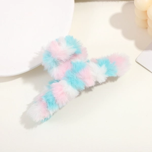 Close-up of pink and blue checkered plush hair claw clip on a white decorative ceramic plate