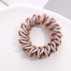 Close-up of tricolor spiral telephone wire hair tie in brown, orange, and purple hues