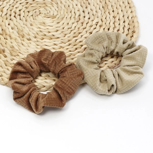 Brown and beige velvet scrunchies set on straw mat for elegant retro hairstyle accessories