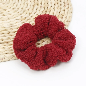 Detail of soft burgundy lamb wool scrunchie with textured fabric on woven mat