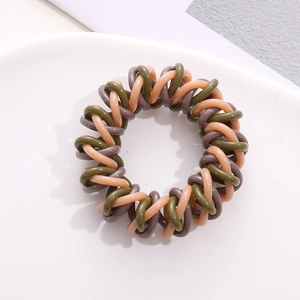 Detailed macro view of spiral telephone wire hair ties in coffee, green, and pink mix