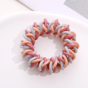 Close-up of pink and purple spiral telephone wire hair ties on a white ceramic plate