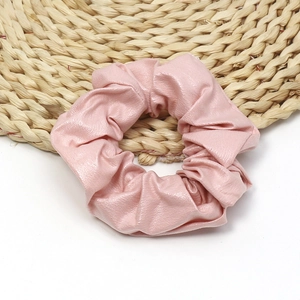 Detail of pink PU leather scrunchie showing refined faux leather texture and soft luster