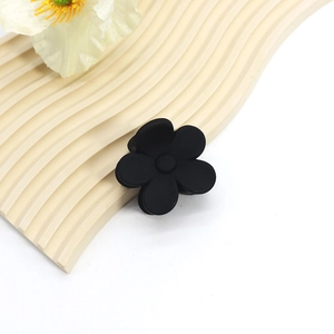 Detailed macro view of a large black matte flower-shaped hair claw clip on a white background