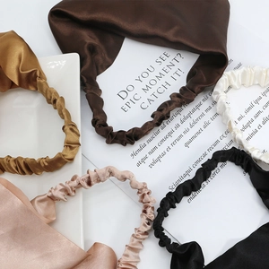 Five-piece satin silk headband set in earth tones arranged elegantly on a white ceramic plate