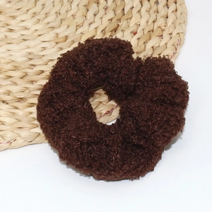 Macro shot of dark brown teddy fleece hair scrunchie with soft fluffy texture on straw mat