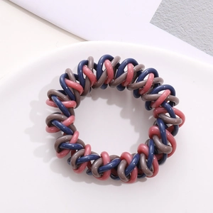 Close-up of tricolor spiral telephone wire hair ties on a minimalist white ceramic tray