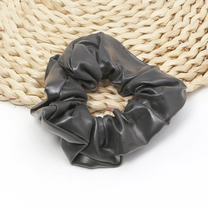 Detailed texture of grey faux leather scrunchie on a woven coaster accessory