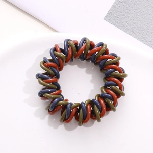 Close-up of spiral telephone wire hair ties in red-brown, olive green, and navy blue tones