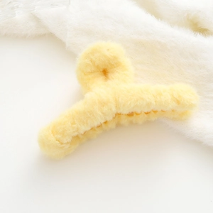 Primo piano di una morbida molletta per capelli in peluche giallo limone con texture in pelliccia