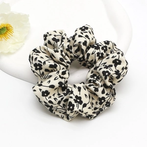 Floral print hair scrunchie with black flowers on white fabric displayed on a tray