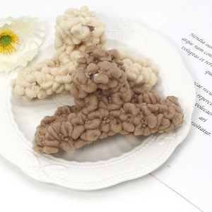 Vue détaillée des pinces à cheveux en peluche tressée beige et marron sur une assiette