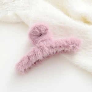 Dettaglio di un fermaglio per capelli in peluche rosa con texture soffice e calda