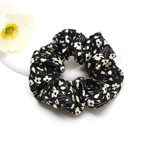 Floral print scrunchie hair tie with white flowers on black cotton fabric in a tray