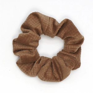 Detail of a brown corduroy hair scrunchie with geometric embossed velvet texture