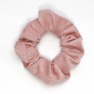 Close-up of pink velvet scrunchie showing fine grid texture and elastic fabric detail