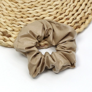 Elegant champagne gold PU leather oversized scrunchie hair tie on woven coaster