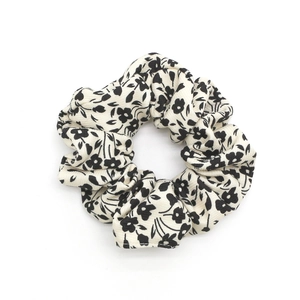 Floral print cotton scrunchie hair tie with black and white daisy pattern on white background