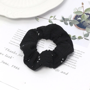 Vue détaillée d'un chouchou noir à pois en coton gaufré avec une texture tricotée