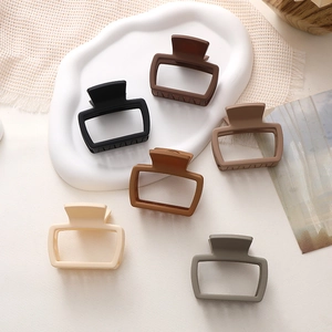 Dettaglio di sei mollette per capelli opache quadrate su vassoio in ceramica e maglia